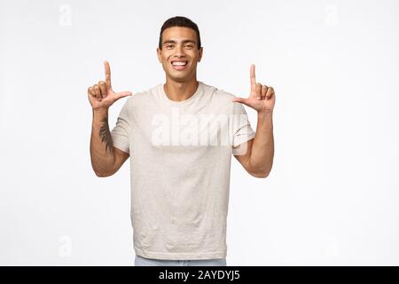 Gutaussehender, fröhlicher, muskulöser junger Mann mit Tattoo, fröhlichem zeigen und Lächeln, Rat Klicken Sie auf den Link, Produkt empfehlen, ADVE Stockfoto