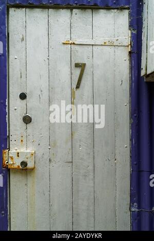 Die Nummer 7 auf einer rustikalen weißen Schuppentür. Stockfoto