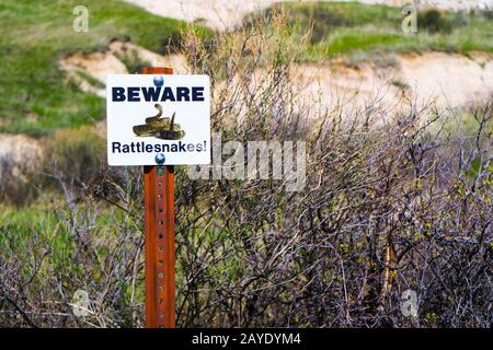 Ein weißes Warnschild mit Logo im Badlands National Park, South Dakota Stockfoto