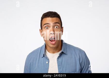 OMG keine Möglichkeit. Beeindruckte, schockierte, ansehnliche Befragte in blauem Hemd über T-Shirt, Sturzbacke staunte, aus Verwunderung a schnappte Stockfoto