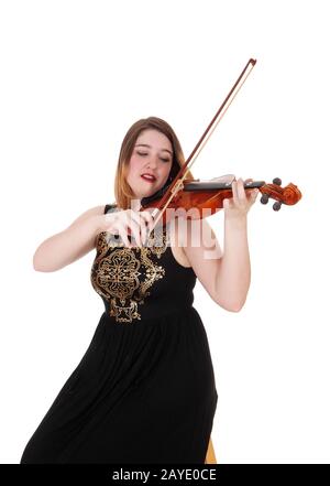 Frau, die in einem langen schwarzen Kleid sitzt und die Geige spielt Stockfoto