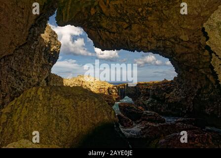 Wasser läuft in Niue in einer Meeresöffnung die freiliegenden Korallenfelsen hinunter Stockfoto