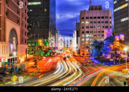 Innenstadt von Osaka im Umeda CBD-Bezirk bei Sonnenuntergang mit verschwommener Straßenkreuzung regulierte Kreuzung zwischen hohen Türmen. Stockfoto