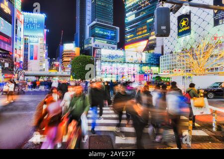 Shibuya, TOKIO, JAPAN - 29. Dezember 2019: Berühmte Shibuya Kreuzung in der Stadt Tokio nachts mit verschwommenen Menschenmassen und hellen Plakaten. Stockfoto