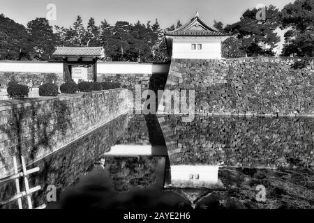 Kontrastreiches Schwarz-Weiß-Bild von starken Steinmauern und breitem Wassergraben rund um das Schloss und den Park von Imperial edo in der Stadt Tokio in Japan. Stockfoto