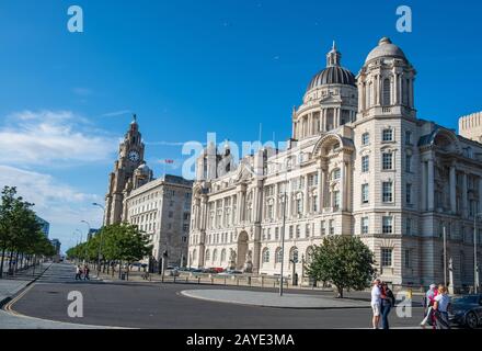 Liverpool Waterfront mit Touristen, die sich und die drei Graces Gebäude in Sicht an einem schönen Sommernachmittag genießen Stockfoto