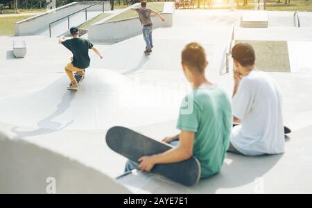 Skater, die mit Skateboard im Stadtpark auftreten - Junge Jungs, die Tricks und Fähigkeiten ausführen - Extreme Sport, Jugend und Freundschaftskonzept - Konzentrieren sich auf Kerl Stockfoto