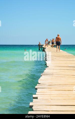 Alcudia, Spanien 14.09.2011 - Menschen zu Fuß auf hölzernen Pier am Meer. Karibische Meer an der Playa de Muro. Touristen vor Ort Stockfoto
