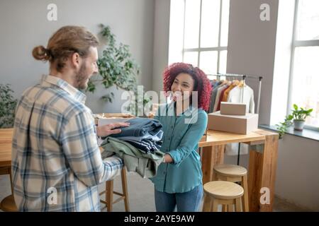 Junge Mädchen und Männer falten Kleidung für einen Benefizverkauf. Stockfoto