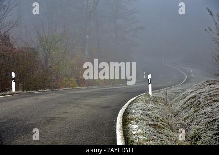 Unfallgefahr durch vereiste Straßen und Nebel auf kurvenreichen Straßen Stockfoto