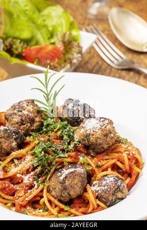 Spaghetti mit Fleischbällchen auf dunklem Holz Stockfoto