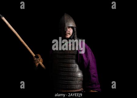 Mann in mittelalterlichen Kleid, lila Hemd, Helm und Kettenpost hält einen Speer Stockfoto