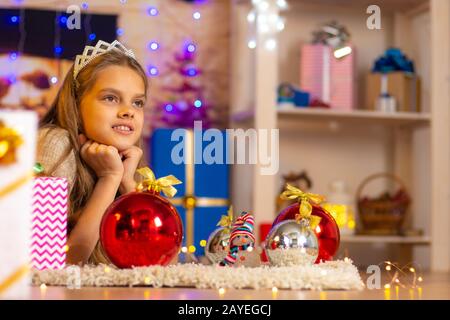 Das schöne zehnjährige Mädchen liegt auf einem Teppich im Neujahrsinnenraum Stockfoto