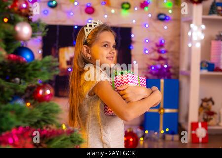 Schöne 10-jährige Mädchen umarmte ein Geschenk Stockfoto