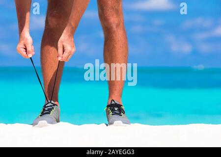 Junge männliche Läufer immer startbereit am weißen Strand Stockfoto