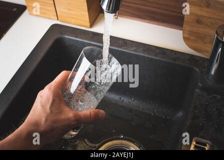 Füllung Glas Wasser aus Edelstahl Küchenarmatur. Trinkwasser Konzept Stockfoto