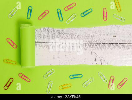 Gerippter Karton mit Büroklammer über einem klassischen Holztisch. Dickes zerrissenes Papier und stationär auf einem strukturierten Holzbackdro Stockfoto