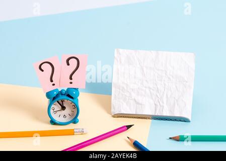 Kleiner Mini-Wecker neben dem stationären, gekippten Wecker. Notizpapier am Rand der leeren einfarbigen Tischkulisse. Stockfoto