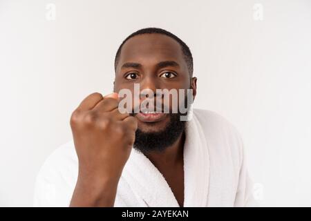 Schwarze Kerl trägt einen Bademantel Zeigefinger mit Überraschung und glückliches Gefühl. Über whtie Hintergrund isoliert. Stockfoto