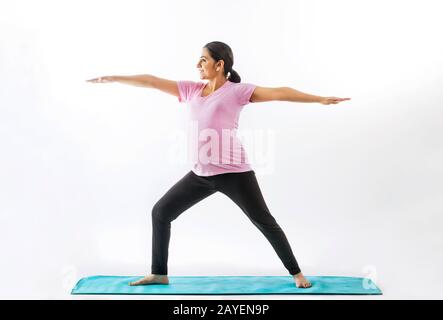 Schwangere Frau, die Yoga in einer Krieger-Position praktiziert. Stockfoto