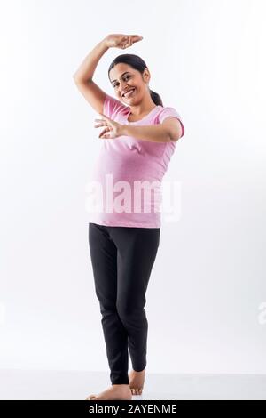 Fröhliche schwangere Frau, die eine klassische Tanzschlamm macht. Stockfoto
