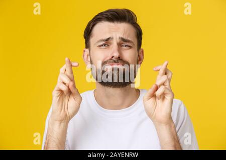 Junger Mann, der einen Wunsch auf gelbem Hintergrund Stockfoto