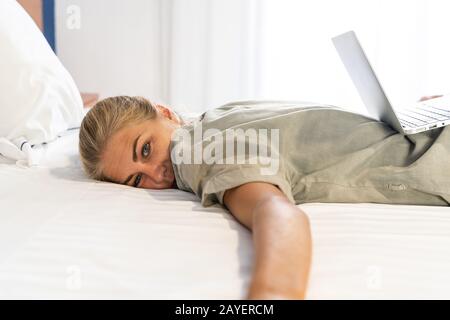 Mädchen müde, ihren Laptop im Bett zu benutzen, weil sie zu viel Arbeit hatte, um zu studieren Stockfoto