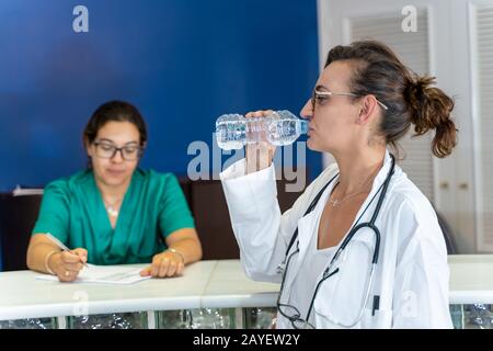 Stockfoto eines Arztes mit Trinkwasser neben einer Krankenschwester in einer Krankenhauslobby Stockfoto