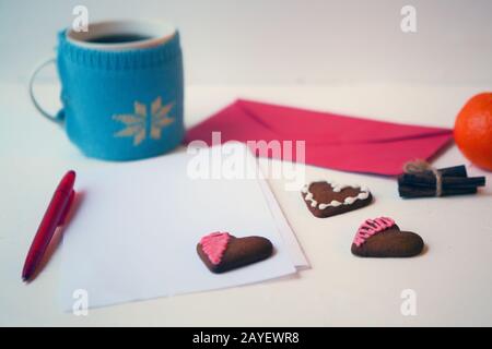 Hearts Lebkuchen Plätzchen mit leerem Buchstaben und Umschlag. Teetasse auf weißem Tisch. Köstliche Hausgemachte Hearts Plätzchen auf weißem Hintergrund. Plätzchen Stockfoto