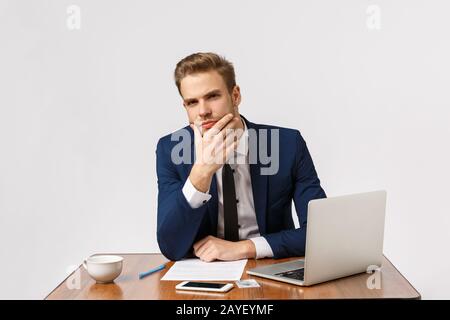 Der Mann, der ernsthafte Gespräche führt, geht davon aus, dass er tief über die Worte von Kollegen nachgedacht hat. Gutaussehender Geschäftsmann im Büro, sitt Stockfoto