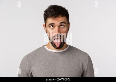 Naheststudio schoss lustigen bärtigen Kerl, der verrückt nach Hause-krank nach Hause ging, Zunge zeigte und Augenlider nach oben rollte, als er goofy, Play machte Stockfoto