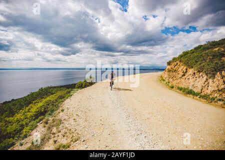 Junger Kerl, der in Spanien auf einem Fahrradweg mit dem Mountainbike-Rad unterwegs ist. Athlet auf einem Mountainbike-Rad fährt vor dem Hintergrund o im Gelände Stockfoto