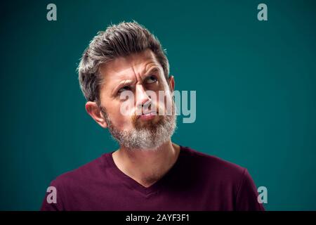 Ein Porträt des nachdenklichen bärtigen Mannes in rotem T-Shirt. Konzept "Menschen und Emotionen" Stockfoto