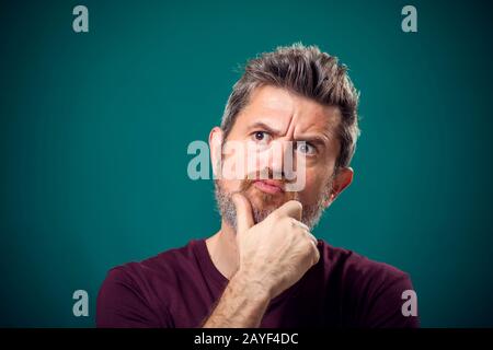 Ein Porträt des nachdenklichen bärtigen Mannes in rotem T-Shirt. Konzept "Menschen und Emotionen" Stockfoto