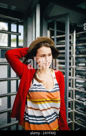 Portrait einer schönen, stilvollen jungen kaukasischen Frau mit einem zauberhaften Lächeln, langen sich entwickelnden Haaren im Wind und einem Strohhut auf Stockfoto