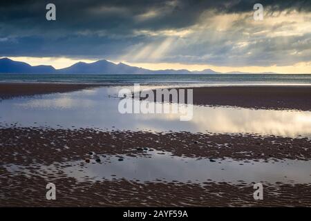 Lichtschächte über der Halbinsel Llŷn, die vom Strand Llanddwyn auf der Insel Anglesey eingenommen wurden. Stockfoto