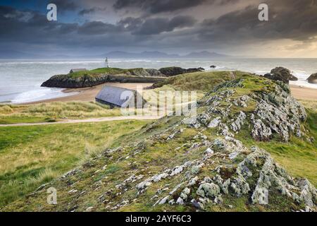 Llanddwyn Island auf der Insel Anglesey mit Snowdonia in der Ferne. Stockfoto