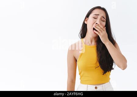 Müde oder gelangweilt attraktive stylische Brunette ostasiatische Frau erschöpft von uninteressanten Gesprächen, schlafend aus Langeweile, gähnendem Neigekopf Stockfoto