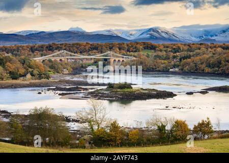 Die Thomas Telford Suspension Bridge nahm von Anglesey mit Snowdonia in der Ferne gefangen. Stockfoto