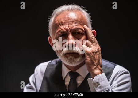 Porträt des pensiven Seniors auf schwarzem Hintergrund. Stockfoto