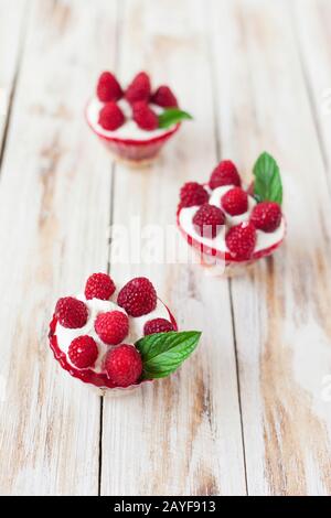 Trifle mit Himbeeren, Minze und Käsekuchen auf altem weißen Holzhintergrund. Traditionelles süßes Dessert in englischer Sprache. Stockfoto