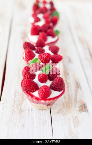 Trifle mit Himbeeren, Minze und Käsekuchen auf altem weißen Holzhintergrund. Traditionelles süßes Dessert in englischer Sprache. Stockfoto