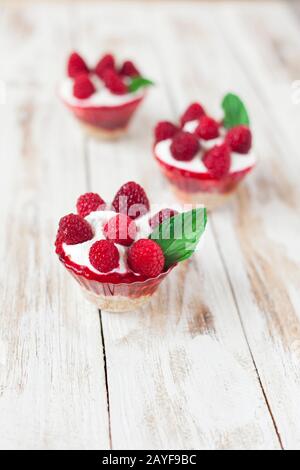 Trifle mit Himbeeren, Minze und Käsekuchen auf altem weißen Holzhintergrund. Traditionelles süßes Dessert in englischer Sprache. Stockfoto