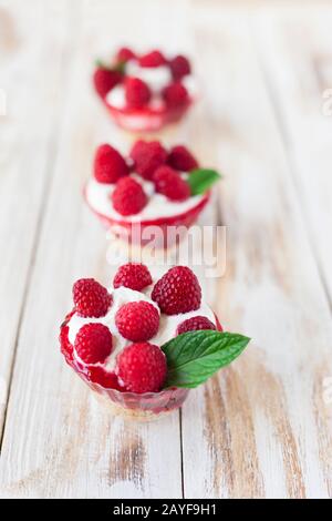 Trifle mit Himbeeren, Minze und Käsekuchen auf altem weißen Holzhintergrund. Traditionelles süßes Dessert in englischer Sprache. Stockfoto