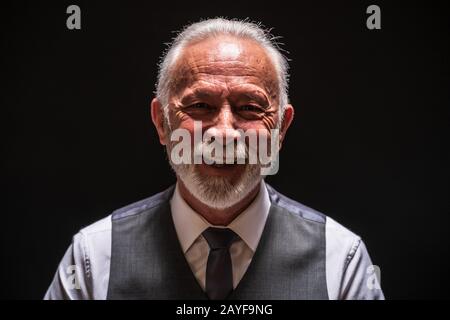 Porträt des fröhlichen Seniors auf schwarzem Hintergrund. Stockfoto