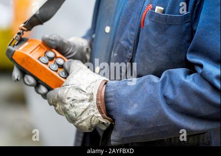 Fernbedienungsschalter mit Außengewinde für Oberkran im Werk, Nahaufnahme. Elektrisches Bedienfeld des Krans und andere Hebezeuge in der Hand des Arbeiter . Stockfoto