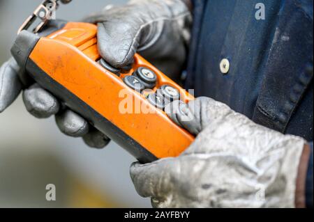 Fernbedienungsschalter mit Außengewinde für Oberkran im Werk, Nahaufnahme. Elektrisches Bedienfeld des Krans und andere Hebezeuge in der Hand des Arbeiter . Stockfoto