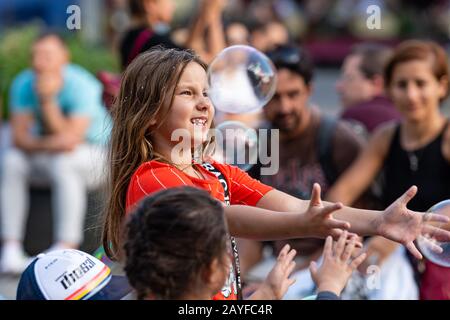 Altstädter Ring, Riga, Lettland - 16. August 2019: Kinder, die mit bunten Seifenblasen spielen, schweben im Vordergrund Stockfoto