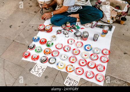 12. JULI 2018, BARCELONA, SPANIEN: Street Beggar verkauft einige handgemachte Kunst für Geld Stockfoto