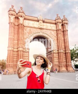 Frau, die selfie gegen die erstaunliche Architektur des Tores Arc de Triomf in Barcelona macht, Stockfoto